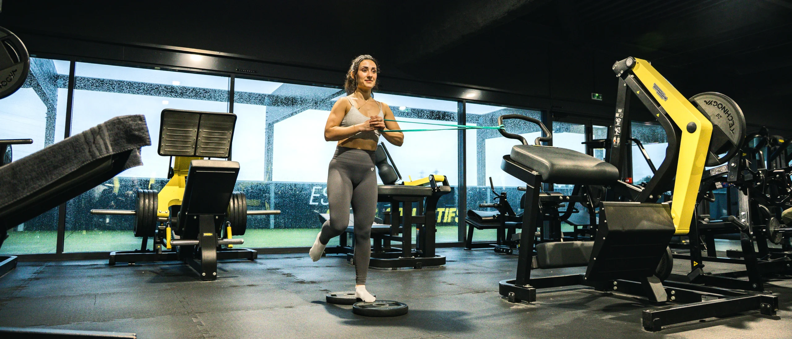 Sportive en salle de sport faisant un exercice d’équilibre et de stabilité avec élastique, entraînement fonctionnel.